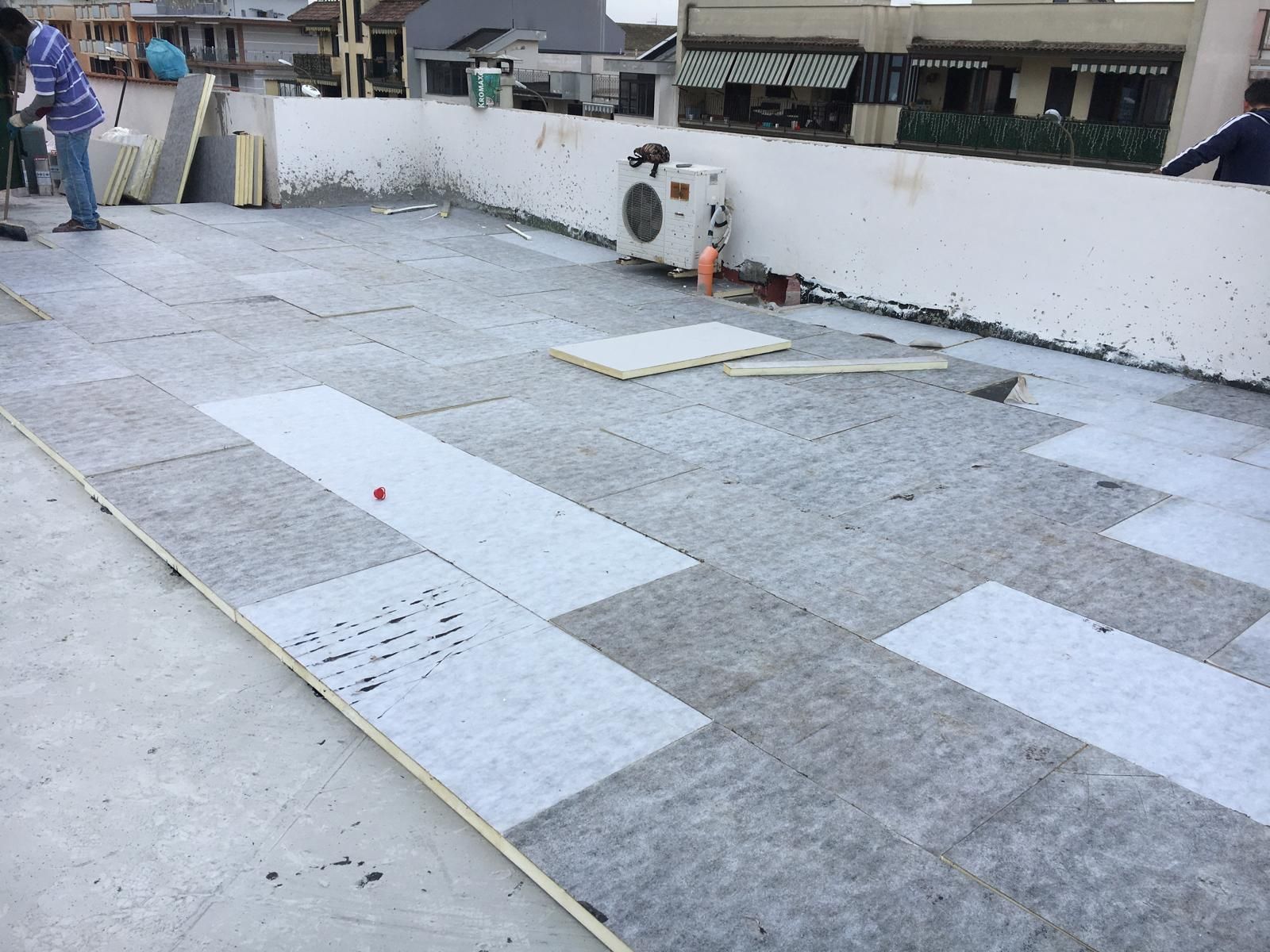 Terrazza sul tetto in costruzione con pavimento grigio, parete bianca e condizionatore d'aria.