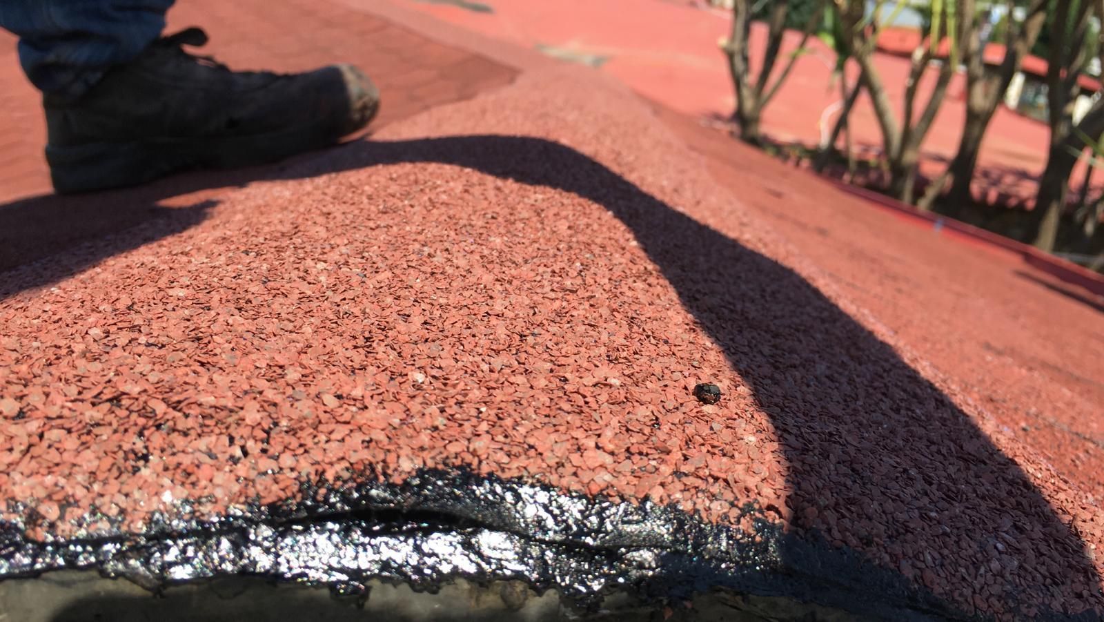 Primo piano di un tetto rosso con una texture particolare, un'ombra scura e una scarpa nell'angolo in alto a sinistra.