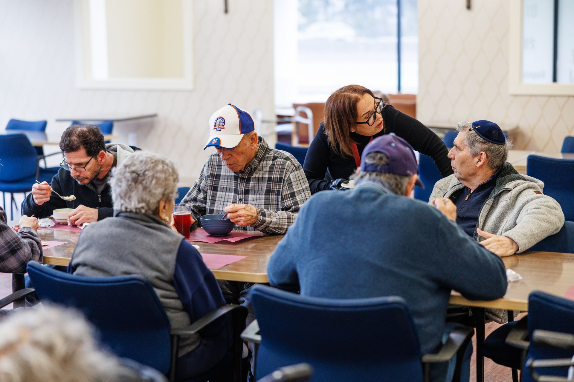 People seated around tables in a bright room, appearing to play a card game