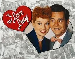 Lucille Ball and Desi Arnaz pose together next to a red heart-shaped