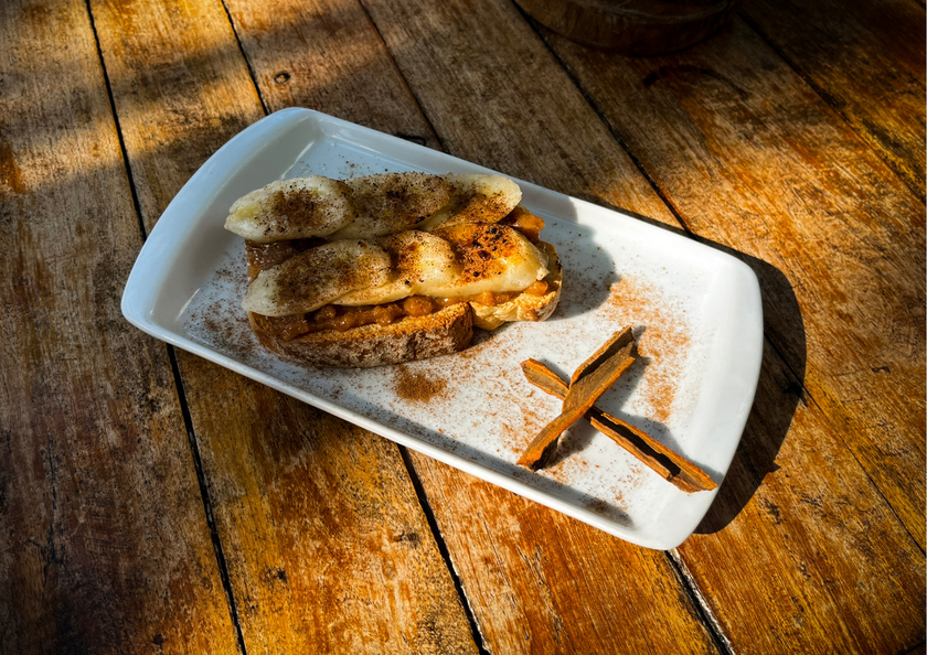 Sobremesa em um prato branco com canela e anis estrelado sobre uma mesa rústica de madeira sob a luz quente do sol.
