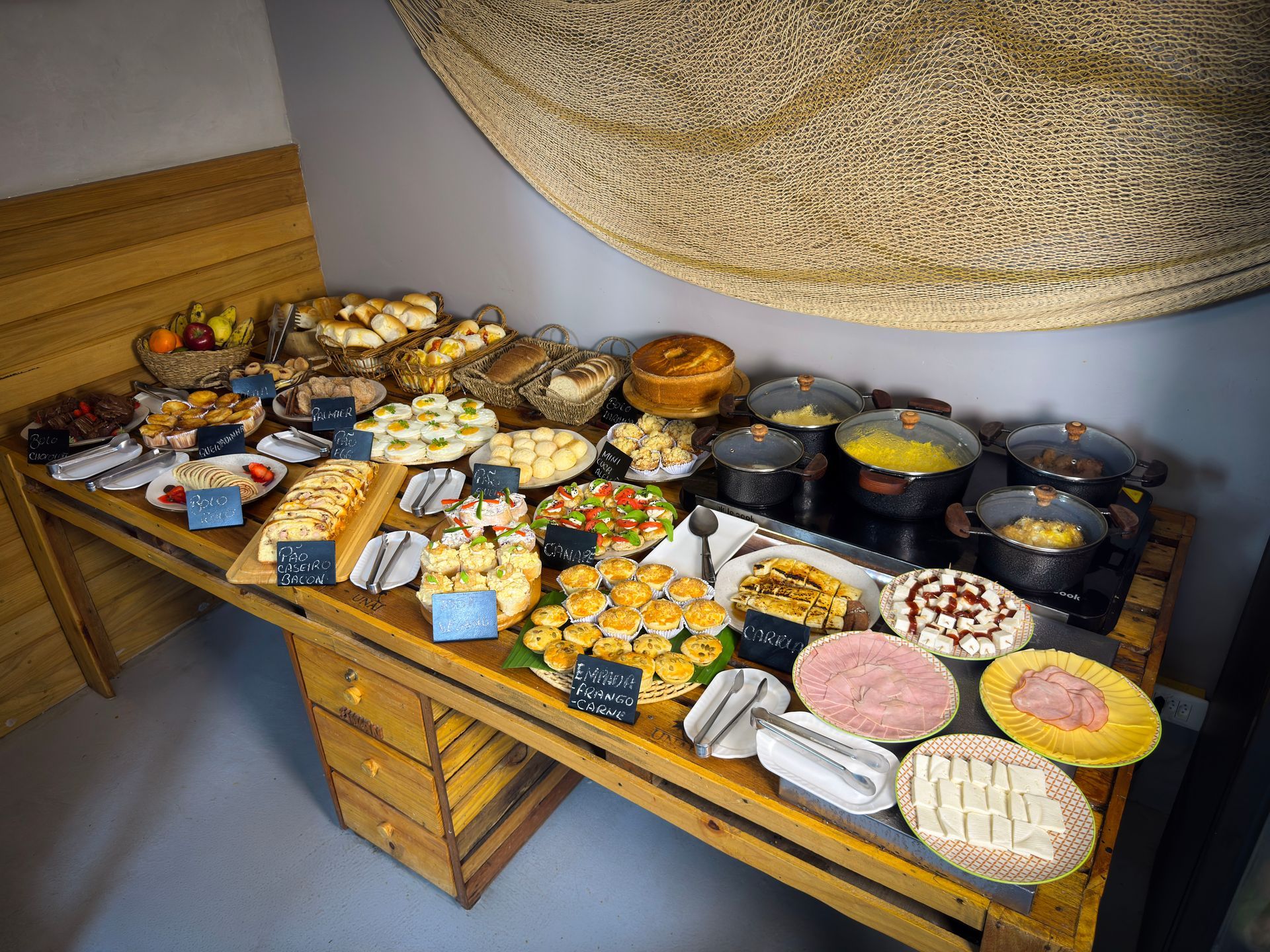 Mesa repleta de doces e sobremesas variadas em bandejas, em um estilo bufê.