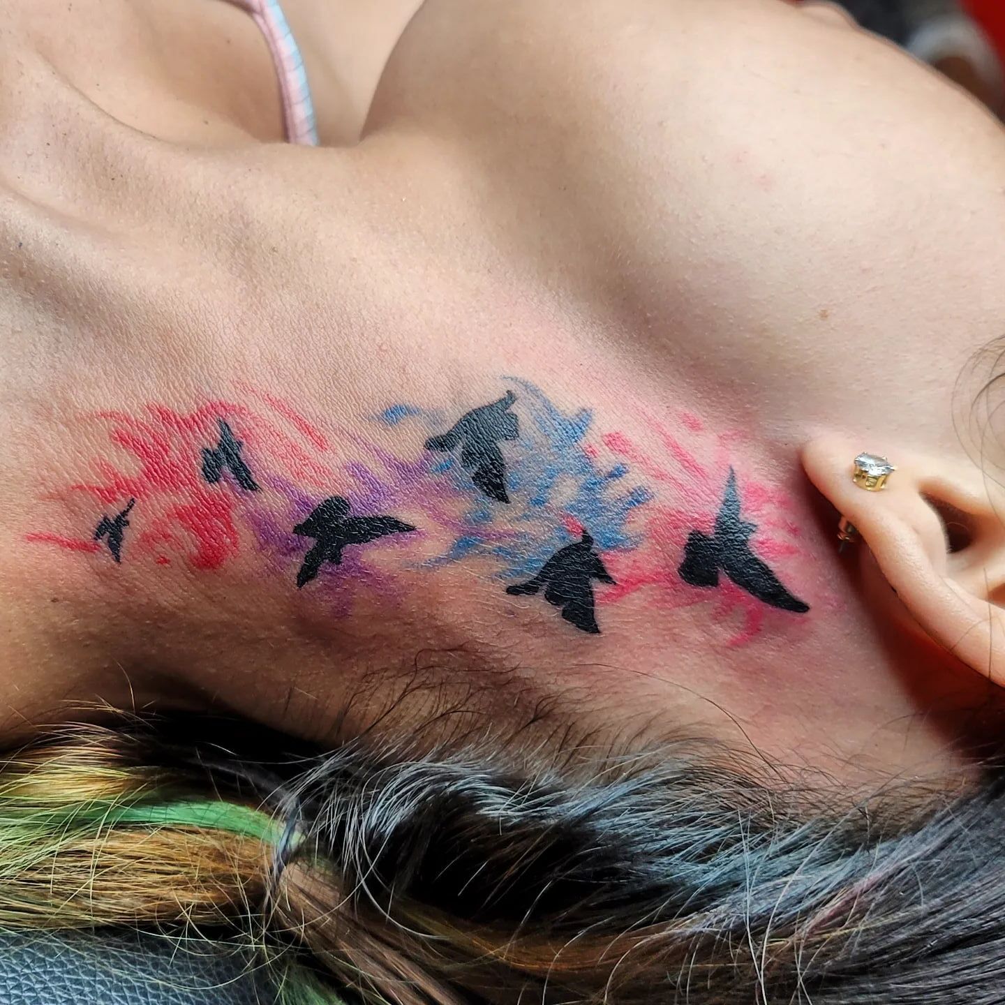 A woman is getting a tattoo on her arm by a tattoo artist.