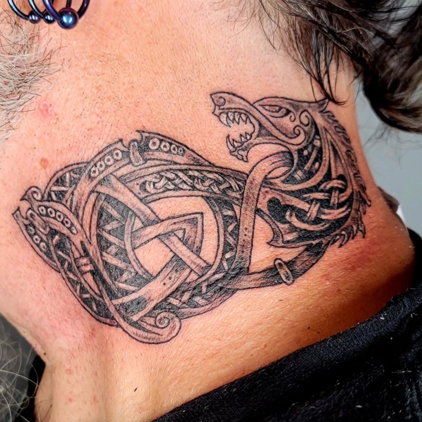 A person has a tattoo of a snake on their finger