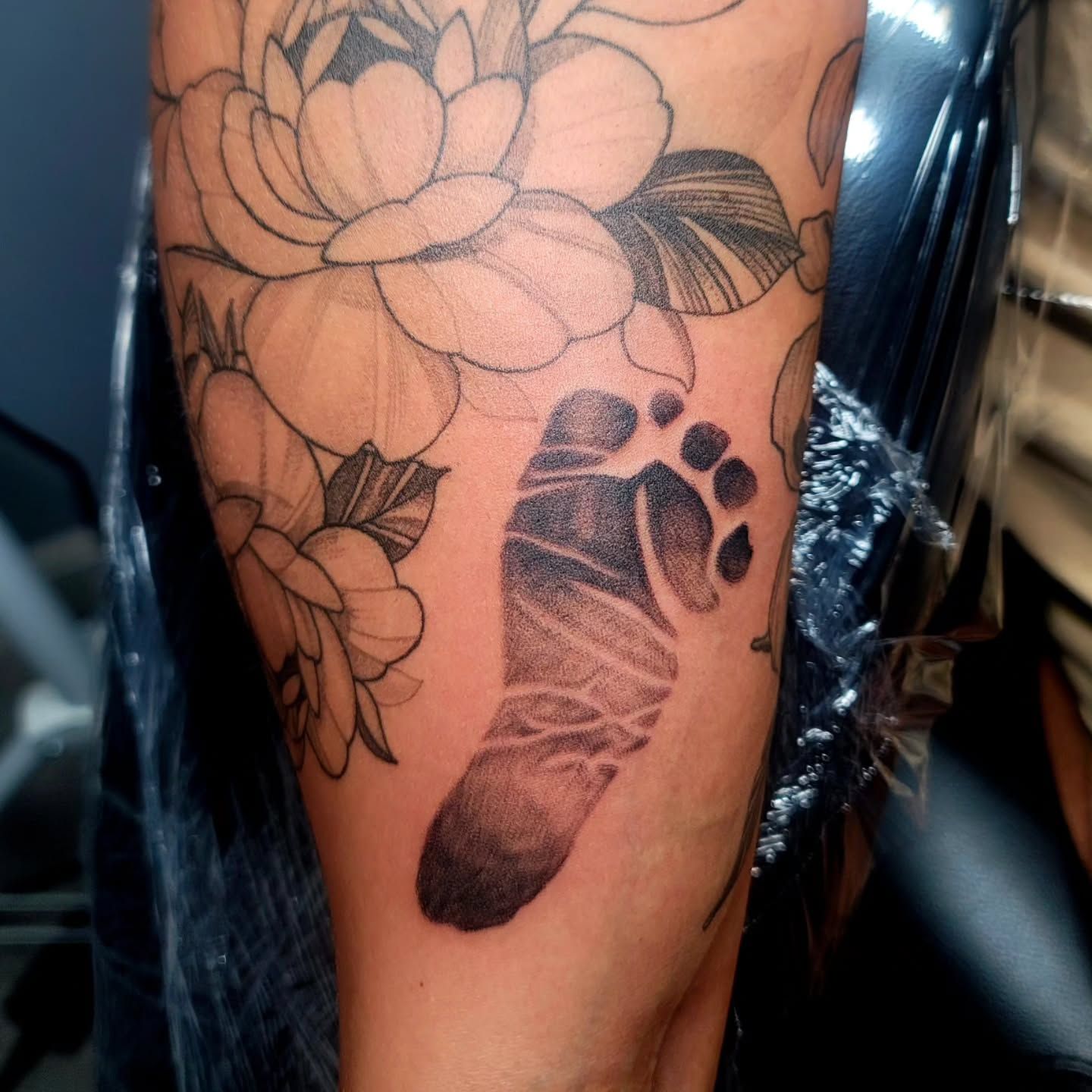 A woman is getting a tattoo on a man's arm.