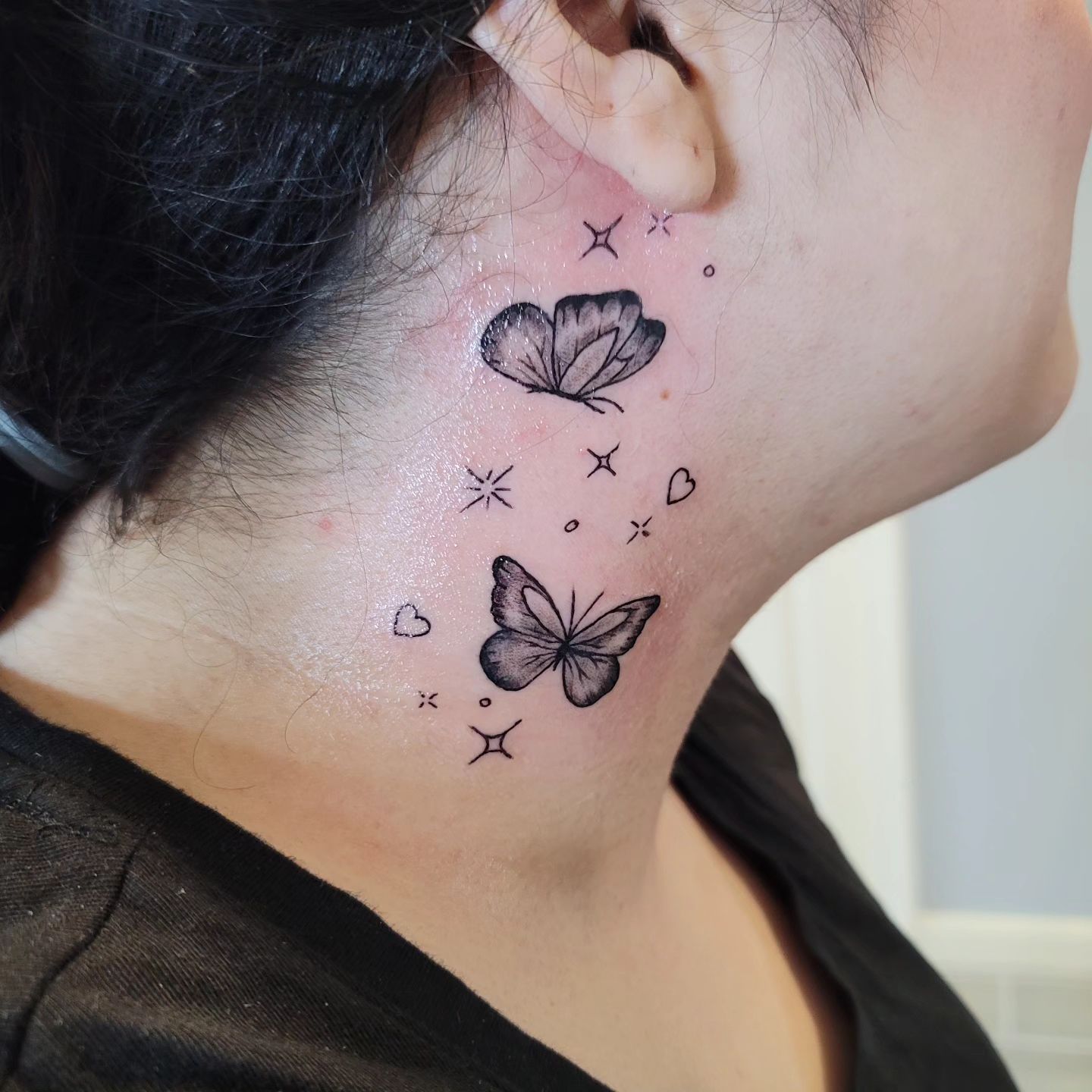 A woman has a tattoo of butterflies on her neck