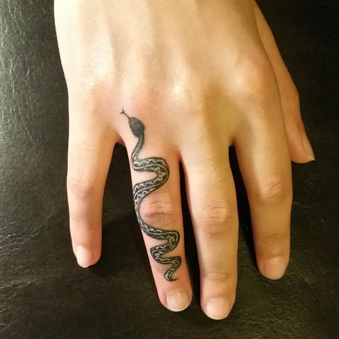 A woman is getting a tattoo on a man's arm.