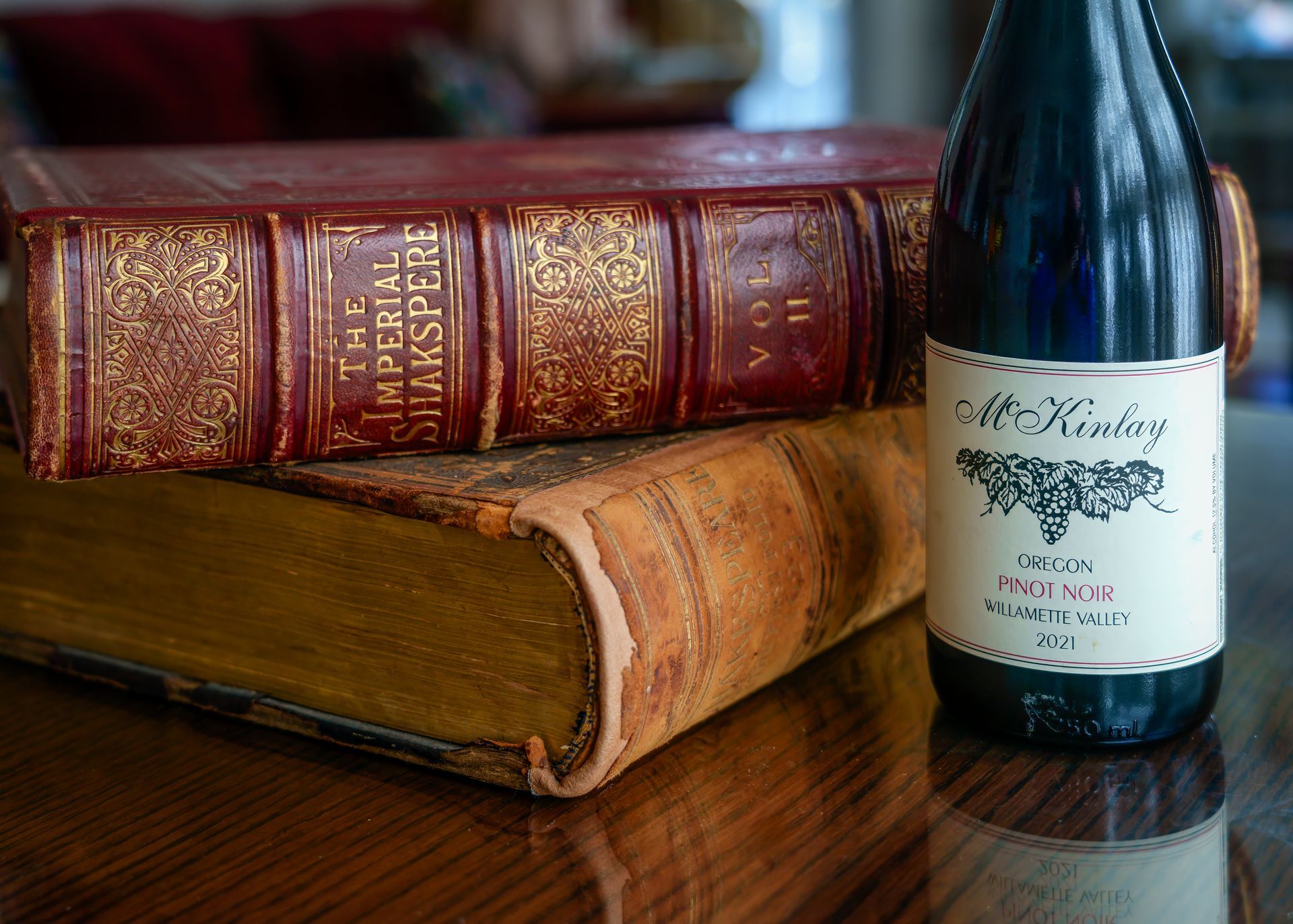 A bottle of wine is sitting next to a book on a table.