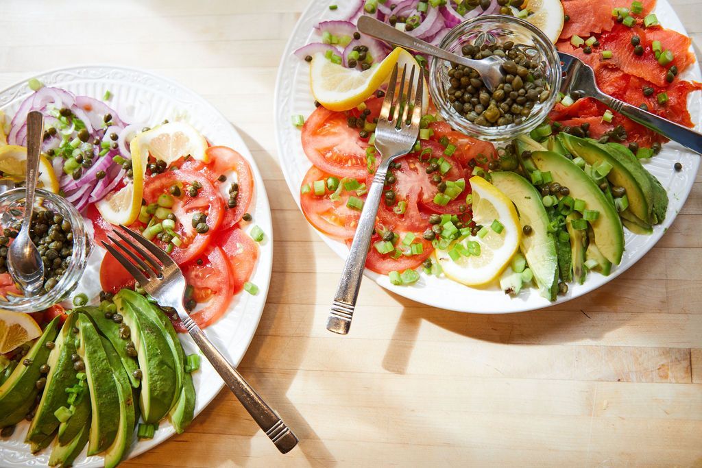 Two plates of food with forks and spoons on a wooden table.