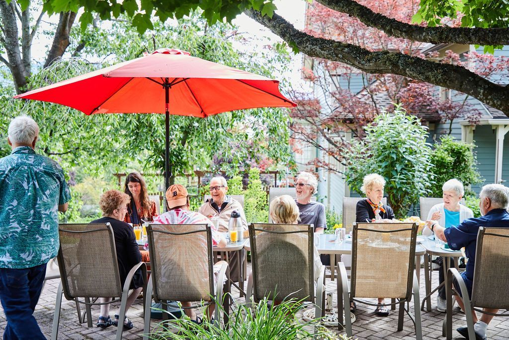 A group of people are sitting at tables under an umbrella.