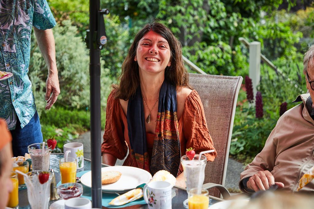 A woman is smiling while sitting at a table with other people.