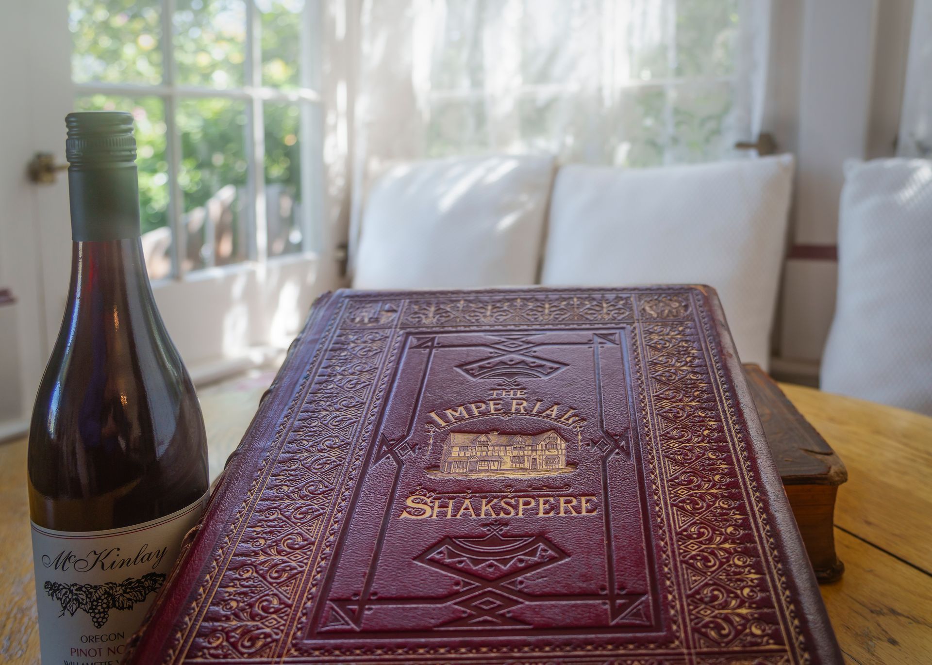 A bottle of wine sits next to a book titled shakespeare