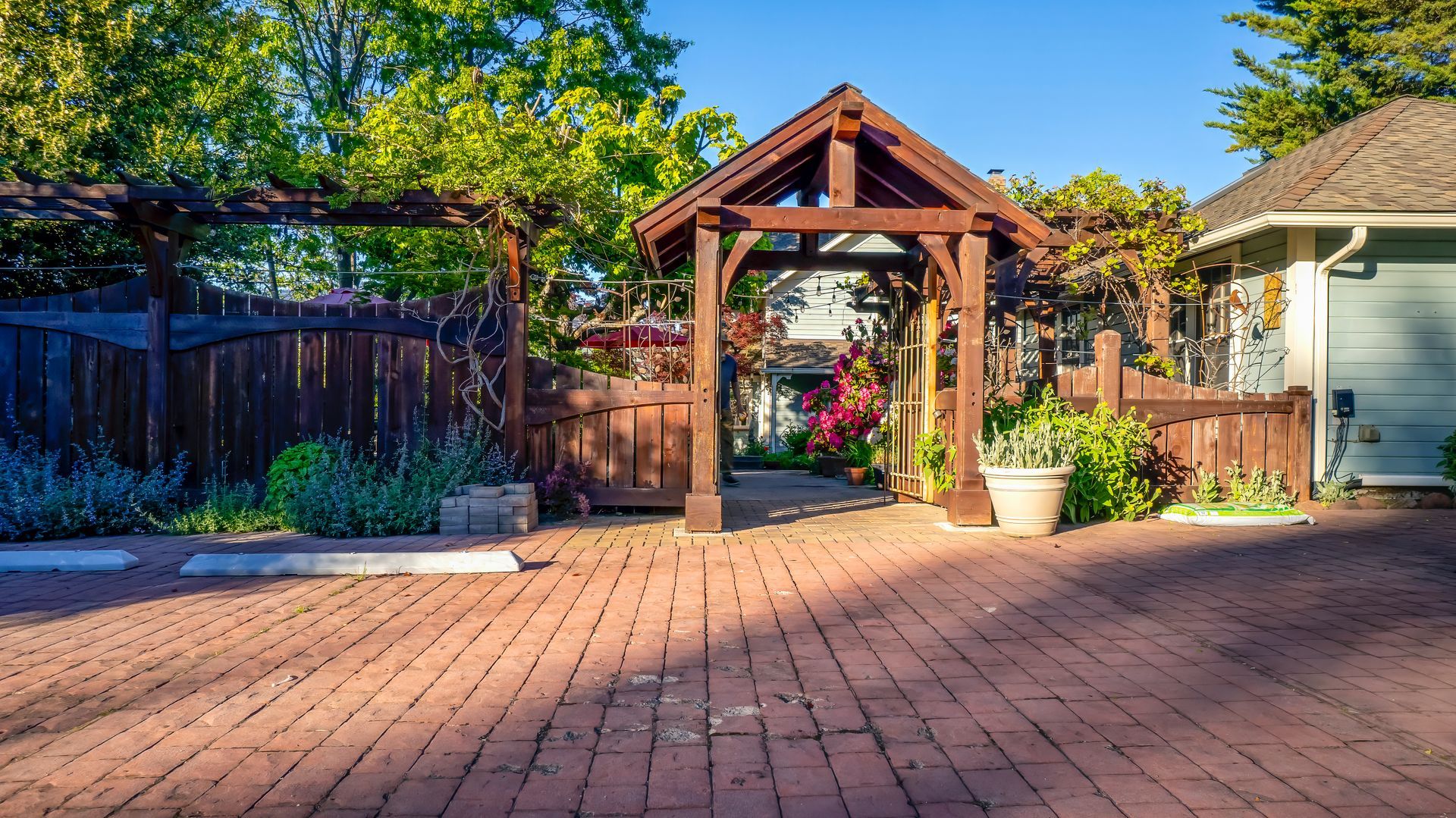 A brick driveway with a wooden gazebo in the background
