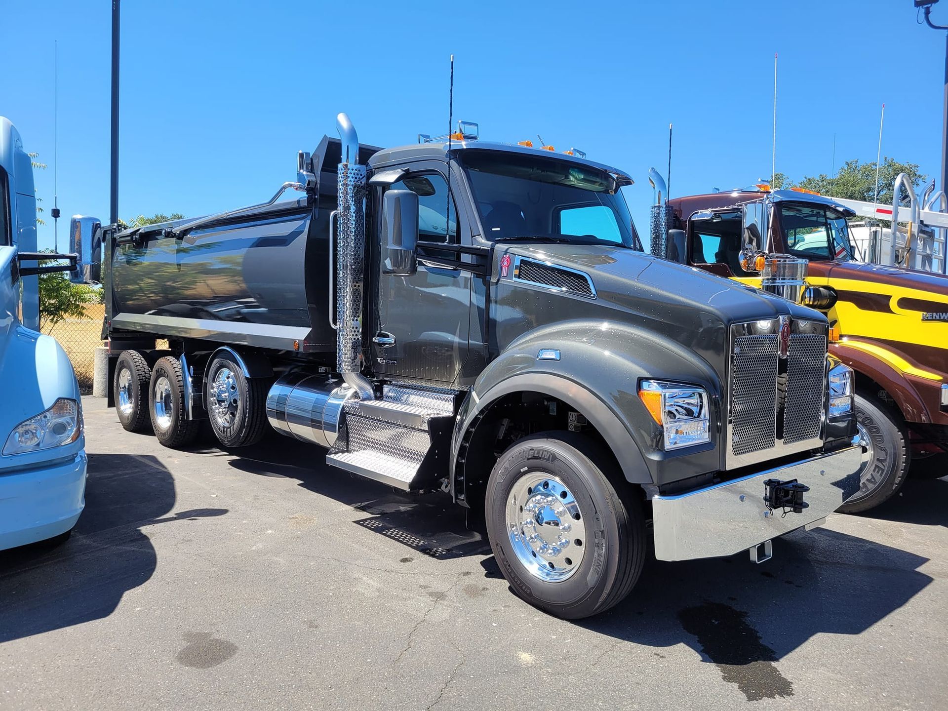 A dump truck is parked in a parking lot next to other trucks.