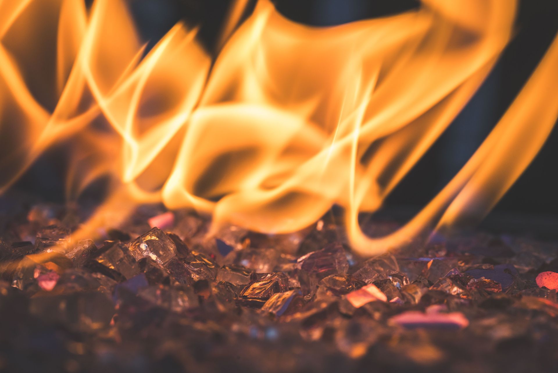 Orange flames rising over glowing embers in a dark fire pit