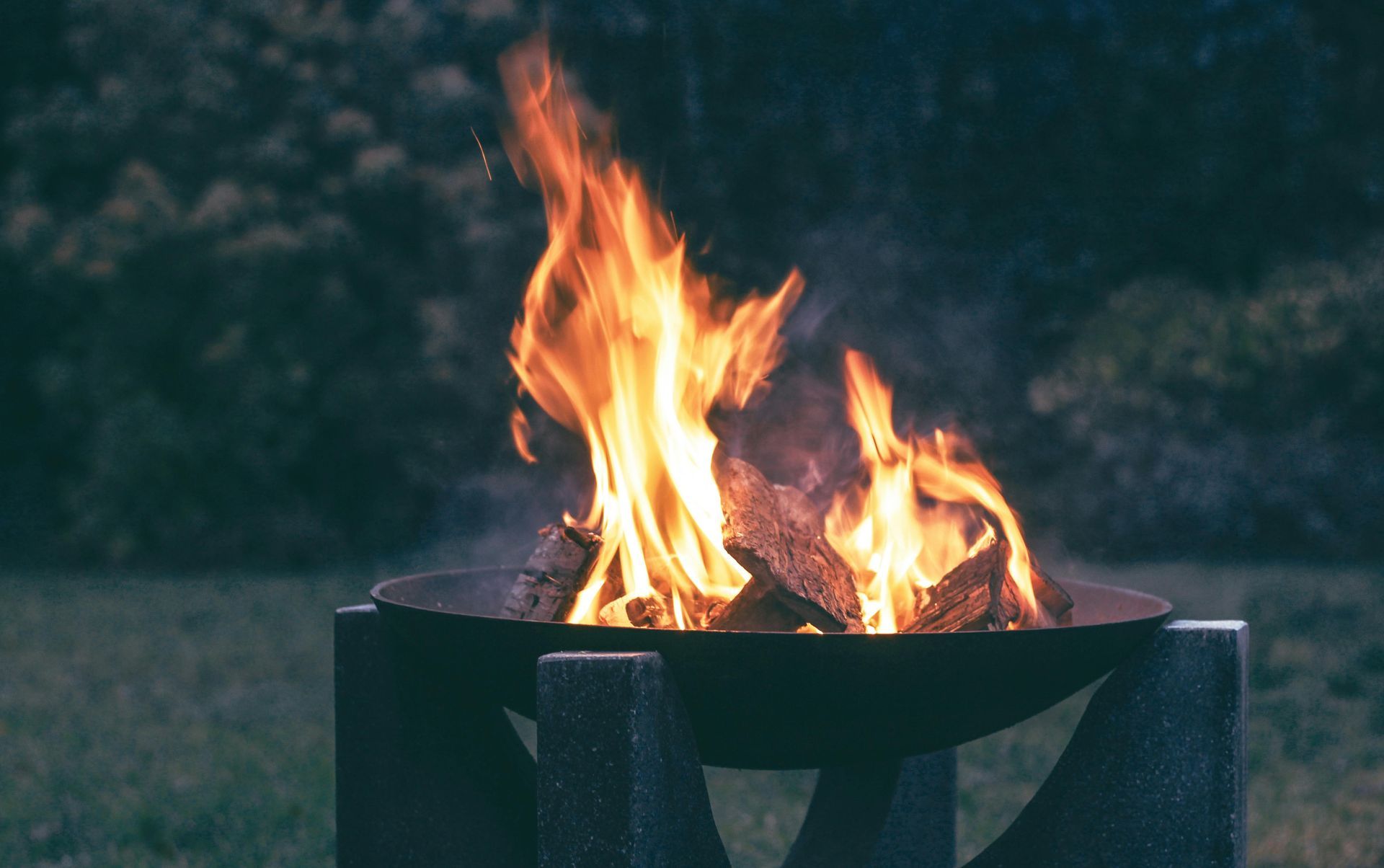 Outdoor fire burning in a metal fire pit at dusk