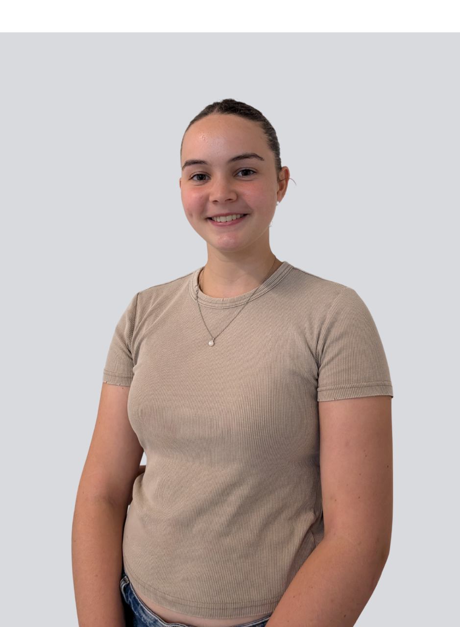 A young woman is wearing a tan t-shirt and a necklace.