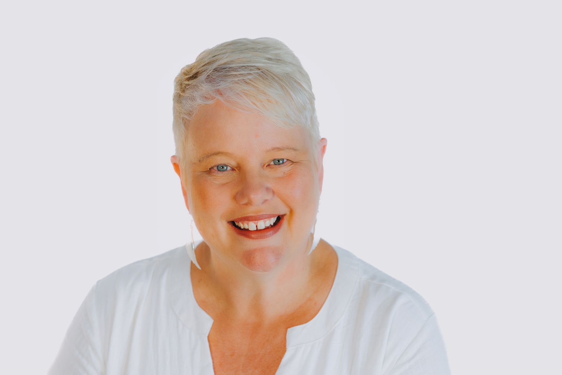A woman in a white shirt is smiling for the camera.