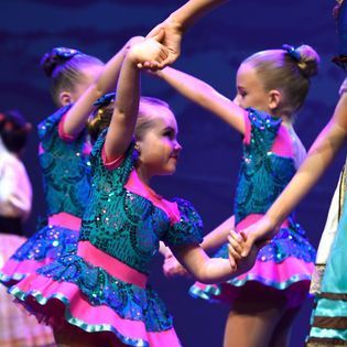 A group of young girls are dancing together on a stage.