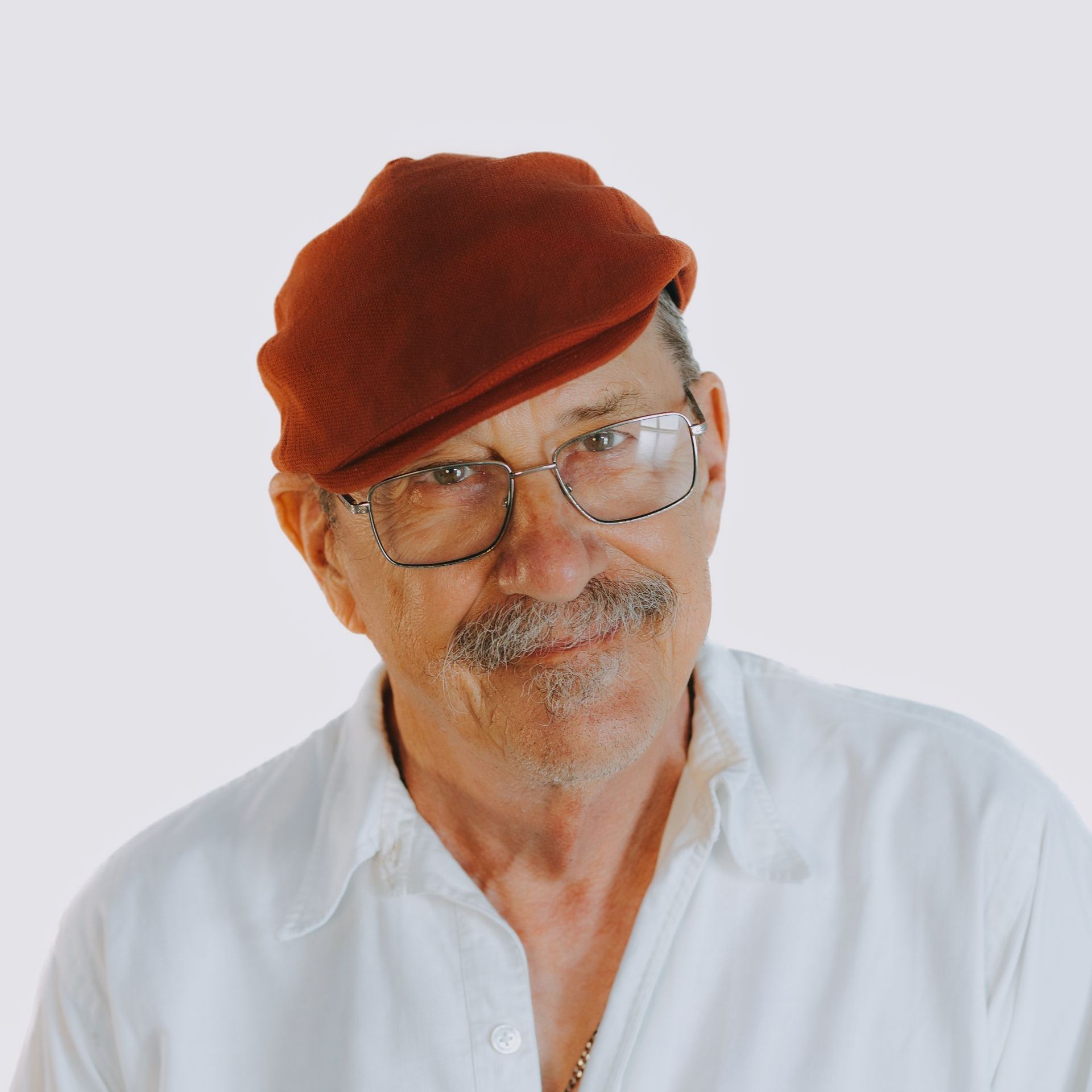 A man wearing a red beret and glasses looks at the camera