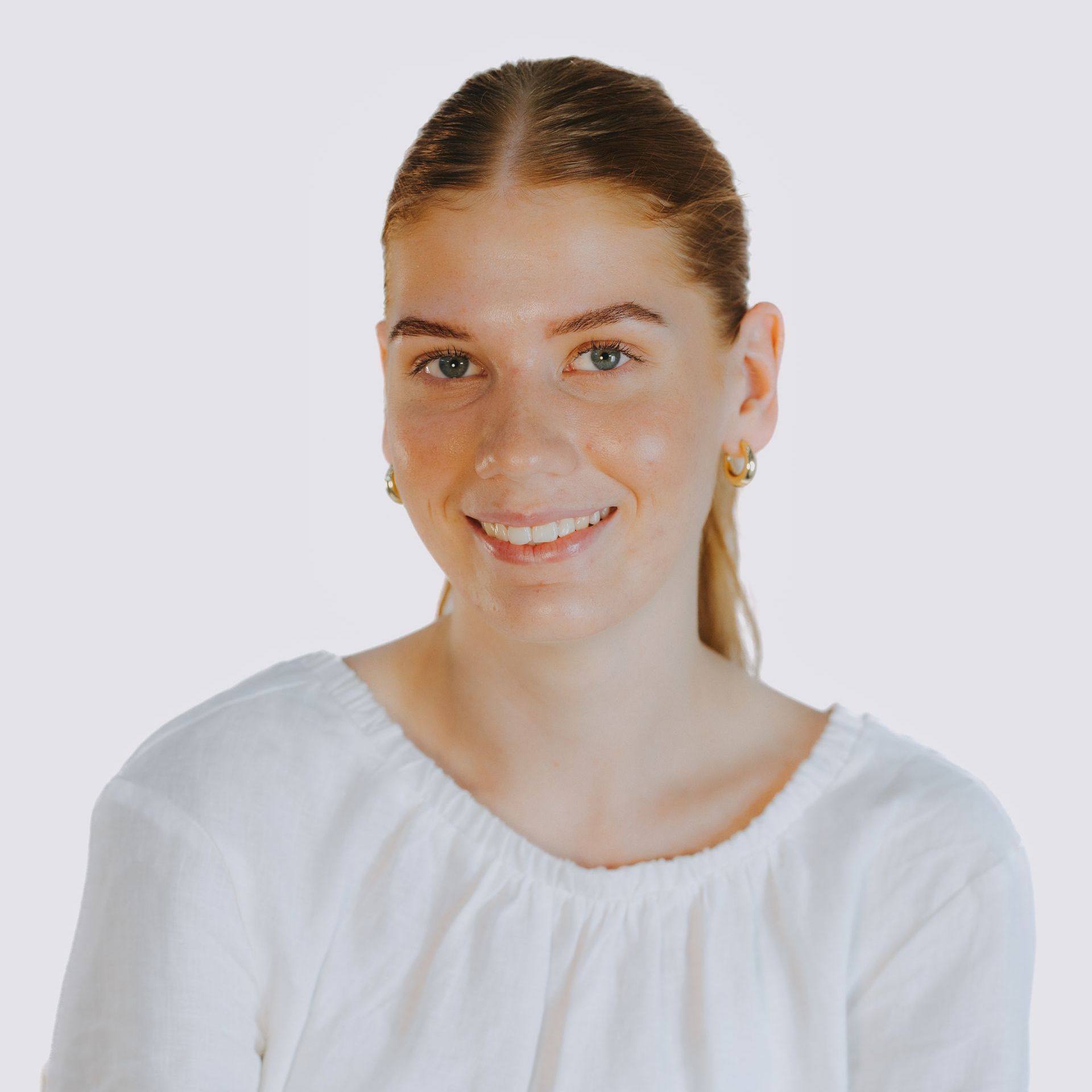 The woman is wearing a white shirt and smiling for the camera.