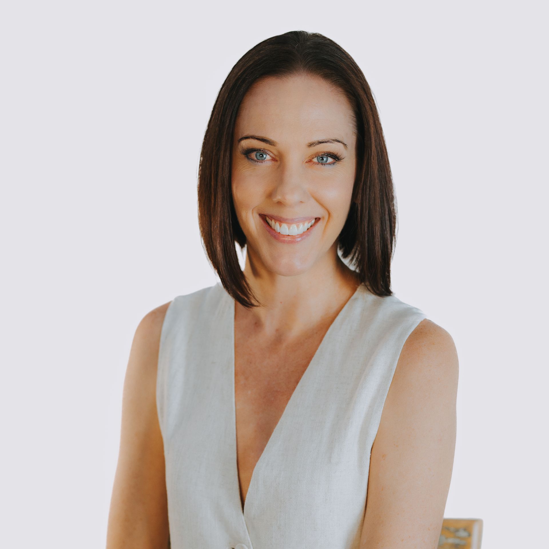 A woman in a white vest is smiling for the camera