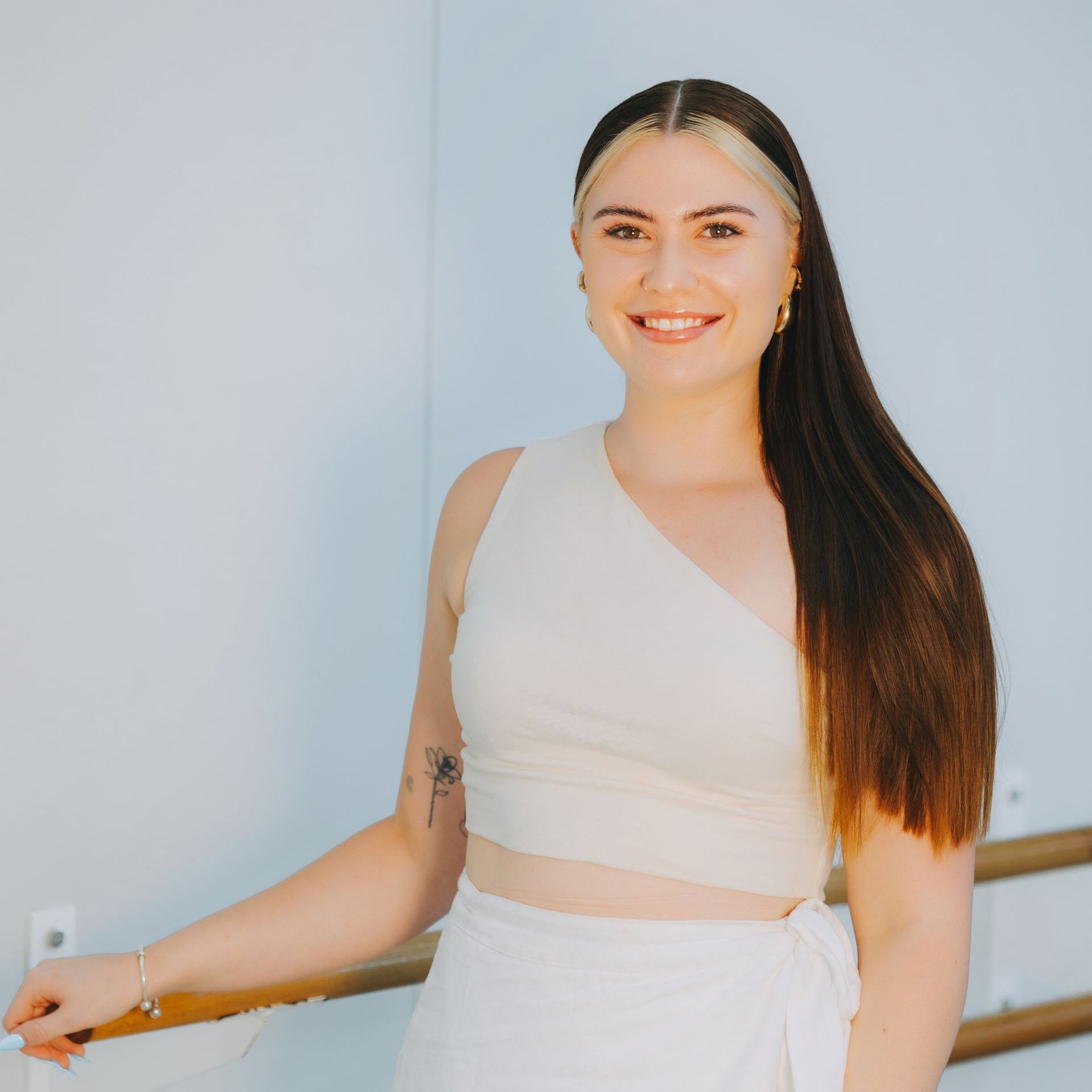 A woman wearing a white crop top and a white skirt
