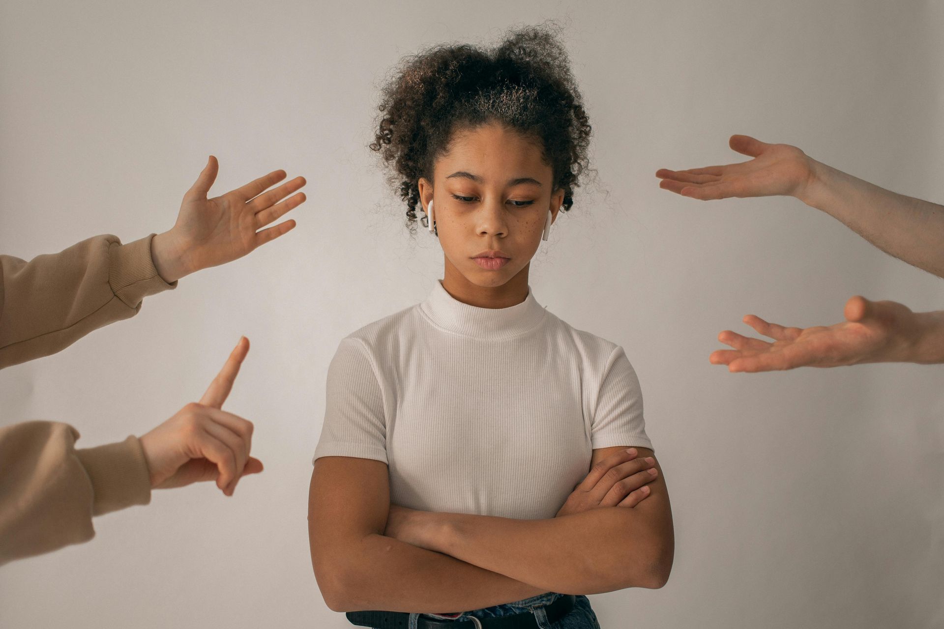 A woman is surrounded by people 's hands pointing at her.