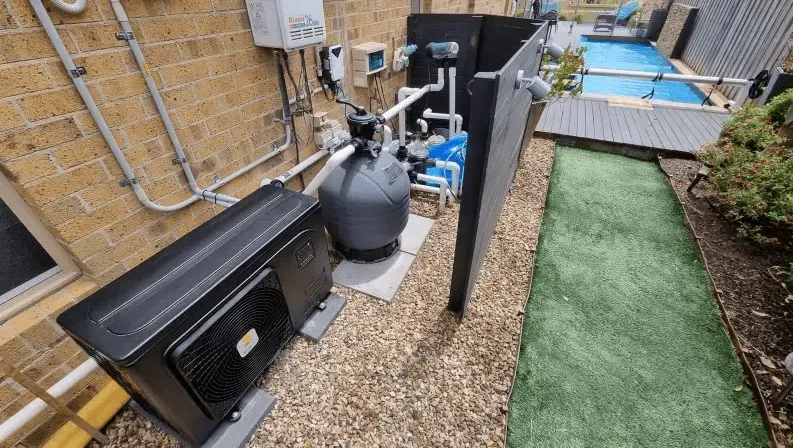 A backyard area showing swimming pool equipment, including a filter, pump, and heat pump, next to a small pool.