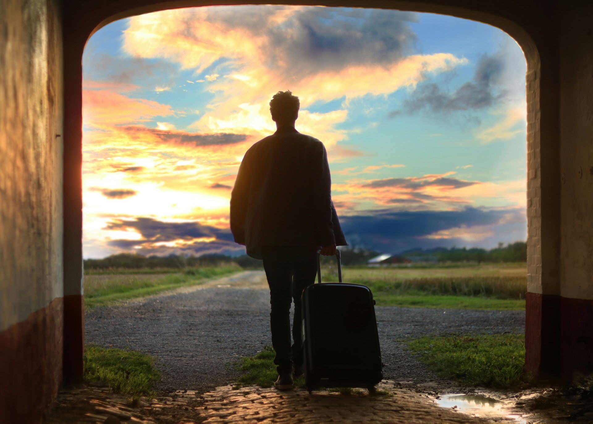 Man with a suitcase looking the nature during the sunset