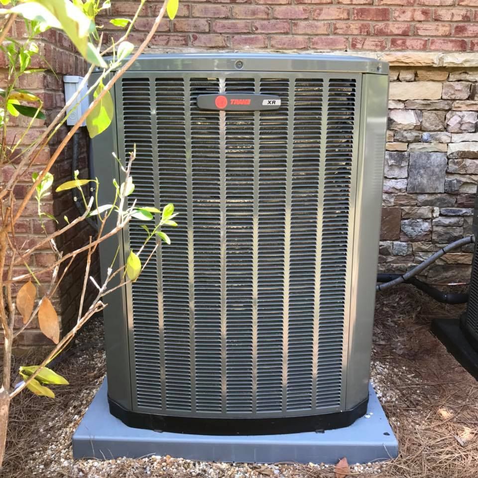 Air Connections Inc - A large air conditioner is sitting outside of a brick building.