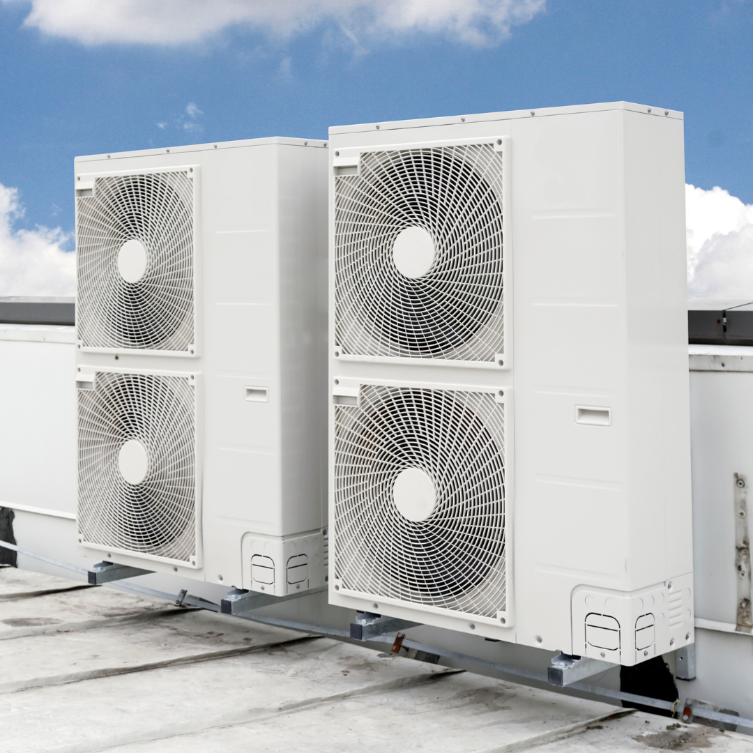 Two white air conditioners are sitting on top of a roof.