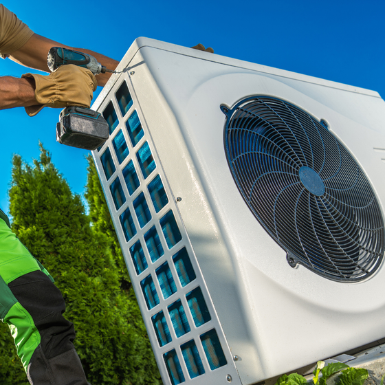 A man is installing an air conditioner with a drill.