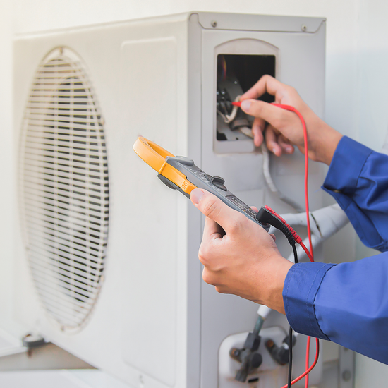 A man is working on an air conditioner with a pair of pliers.