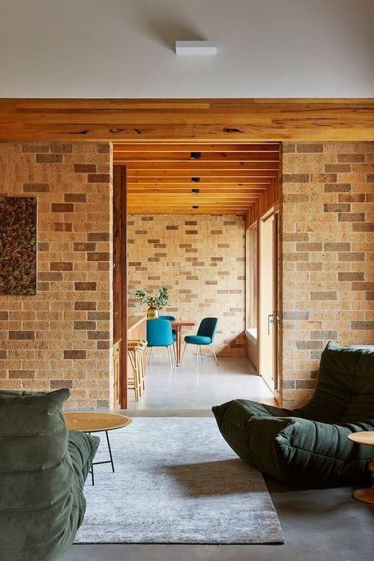 A Living Room With A Brick Wall And Wooden Beams Leading To A Dining Room — Southern Bricks & Pavers In Ulladulla, NSW
