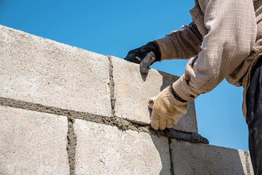 A Man Is Laying Bricks On A Wall — Southern Bricks & Pavers In Moruya, NSW