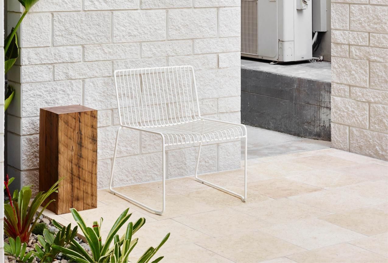 A White Chair Is Sitting On A Patio Next To A Brick Wall — Southern Bricks & Pavers In Ulladulla, NSW