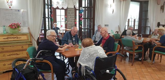 Un gruppo di persone sedute a dei tavoli in una stanza luminosa e ben illuminata, impegnate in attività o conversazioni.