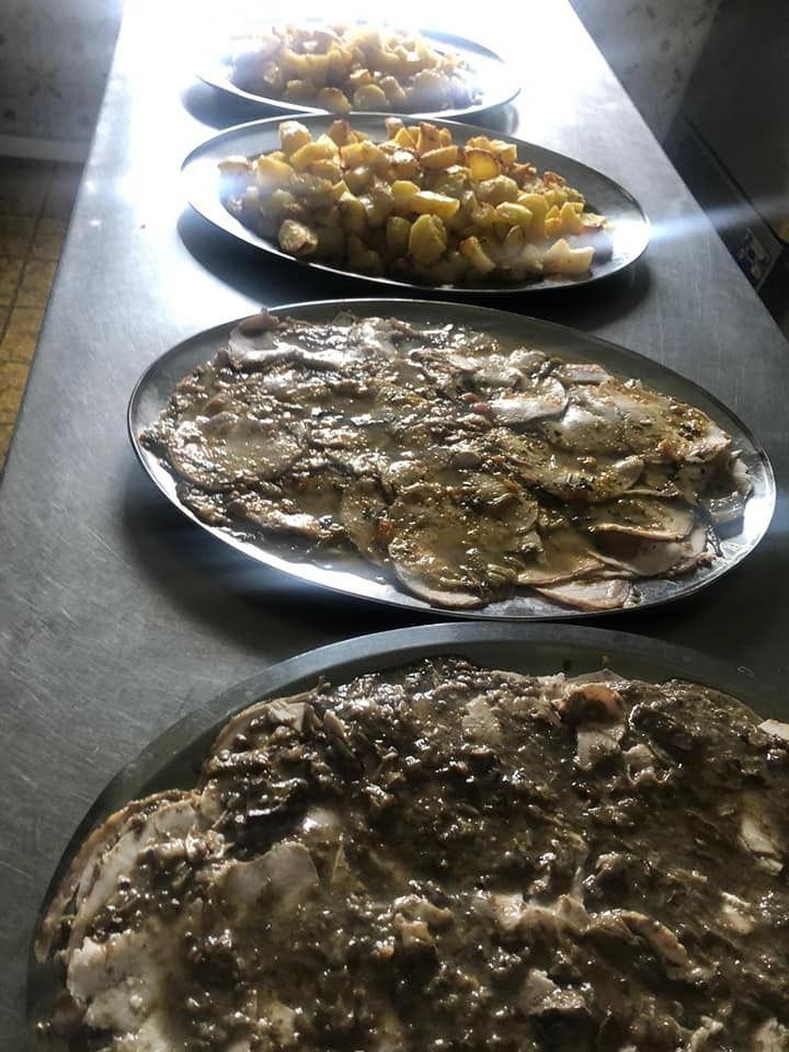 Quattro vassoi da portata disposti su un tavolo, con patate arrosto e carne affettata ricoperta da una salsa marrone scuro.