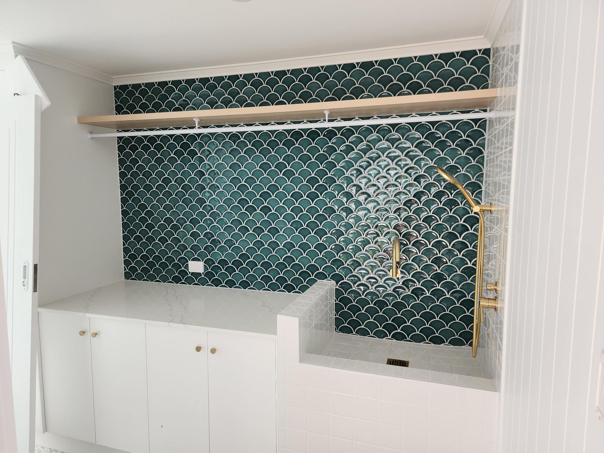 Modern kitchen with white cabinets, green patterned tile backsplash, and brass fixtures