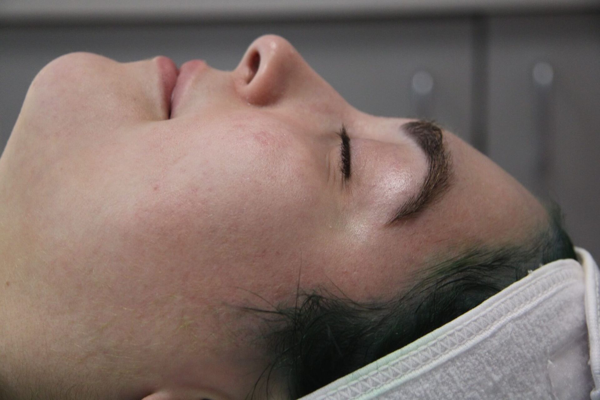 Woman's face, eyes closed, angled upwards. Resting on a towel, neutral expression.