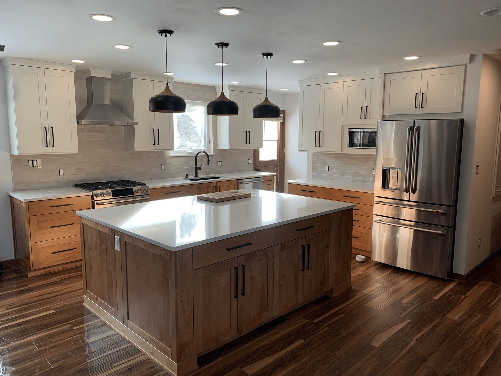 Modern white kitchen with sleek cabinetry, a central island, and open shelving filled with kitchenware and appliances.