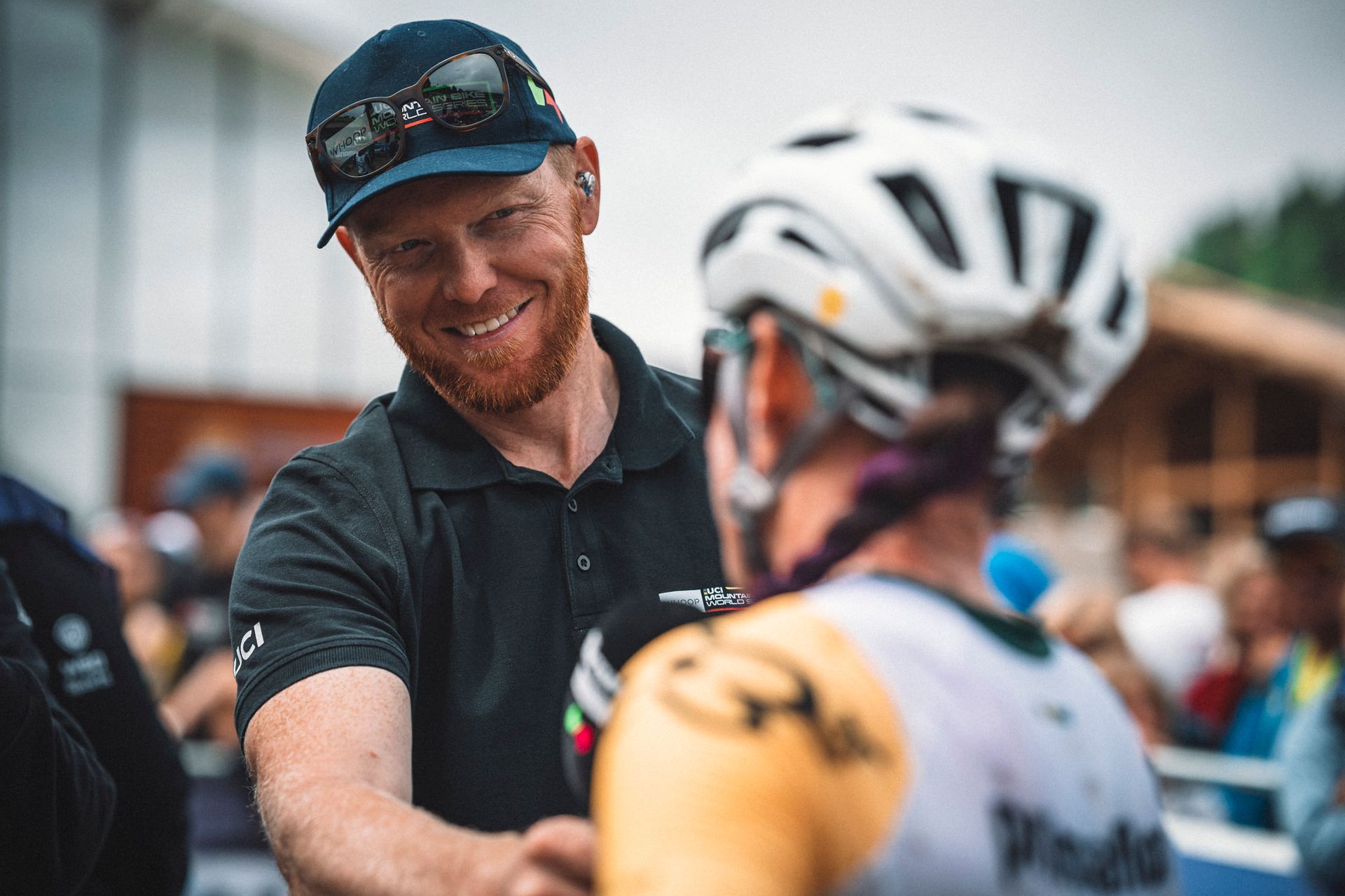 A man is shaking hands with a bicycle racer wearing a helmet.