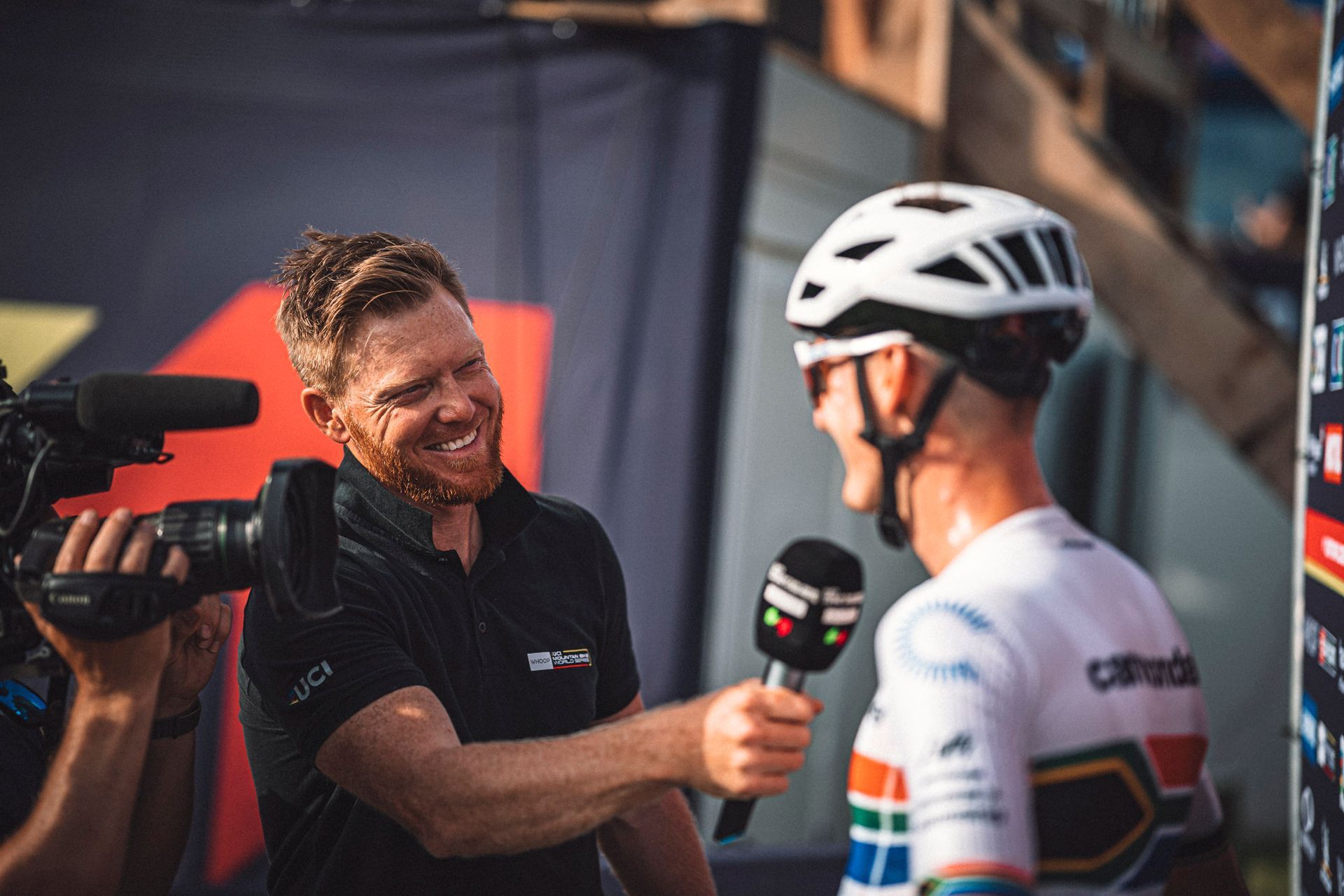 A man is holding a microphone and talking to a bicycle racer.