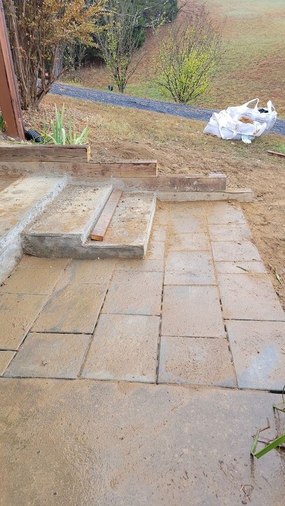 Stone patio and steps leading to a grassy yard, with a white plastic bag on the right.