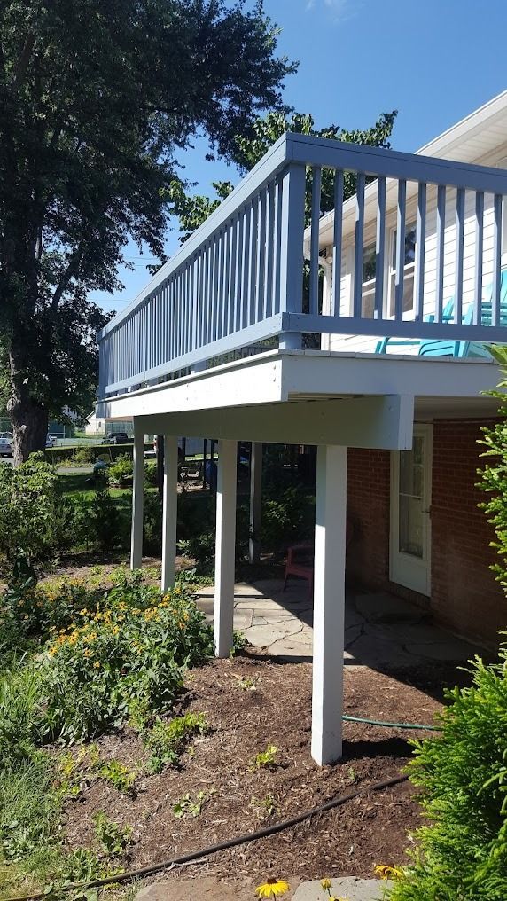 Elevated apartment balcony with blue railing above a landscaped garden walkway