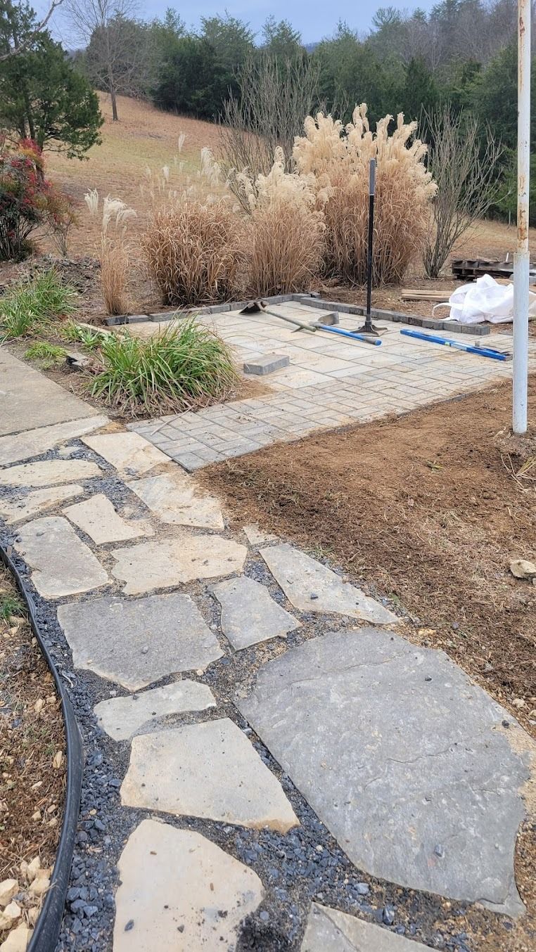 Stone garden path beside dry ornamental grasses and a landscaped yard on a sunny day