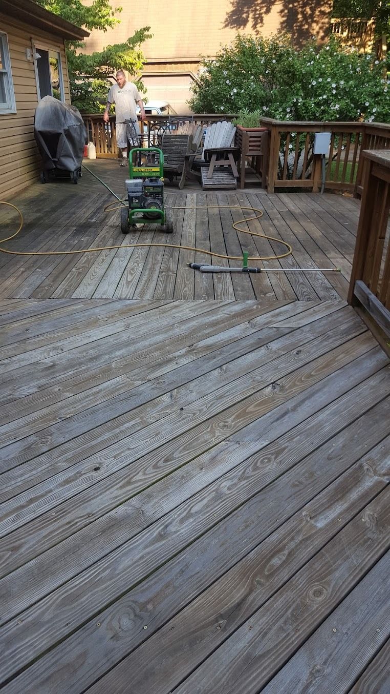 Wooden backyard deck with a grill, chairs, and potted plants in warm evening light