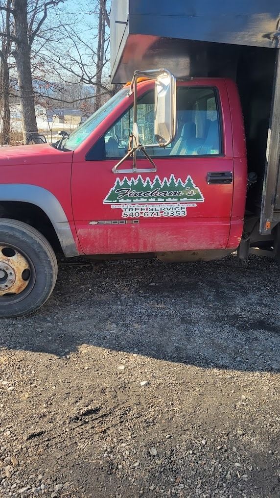 Red utility truck parked on gravel, side view, with a large black bed and company logo on the door.