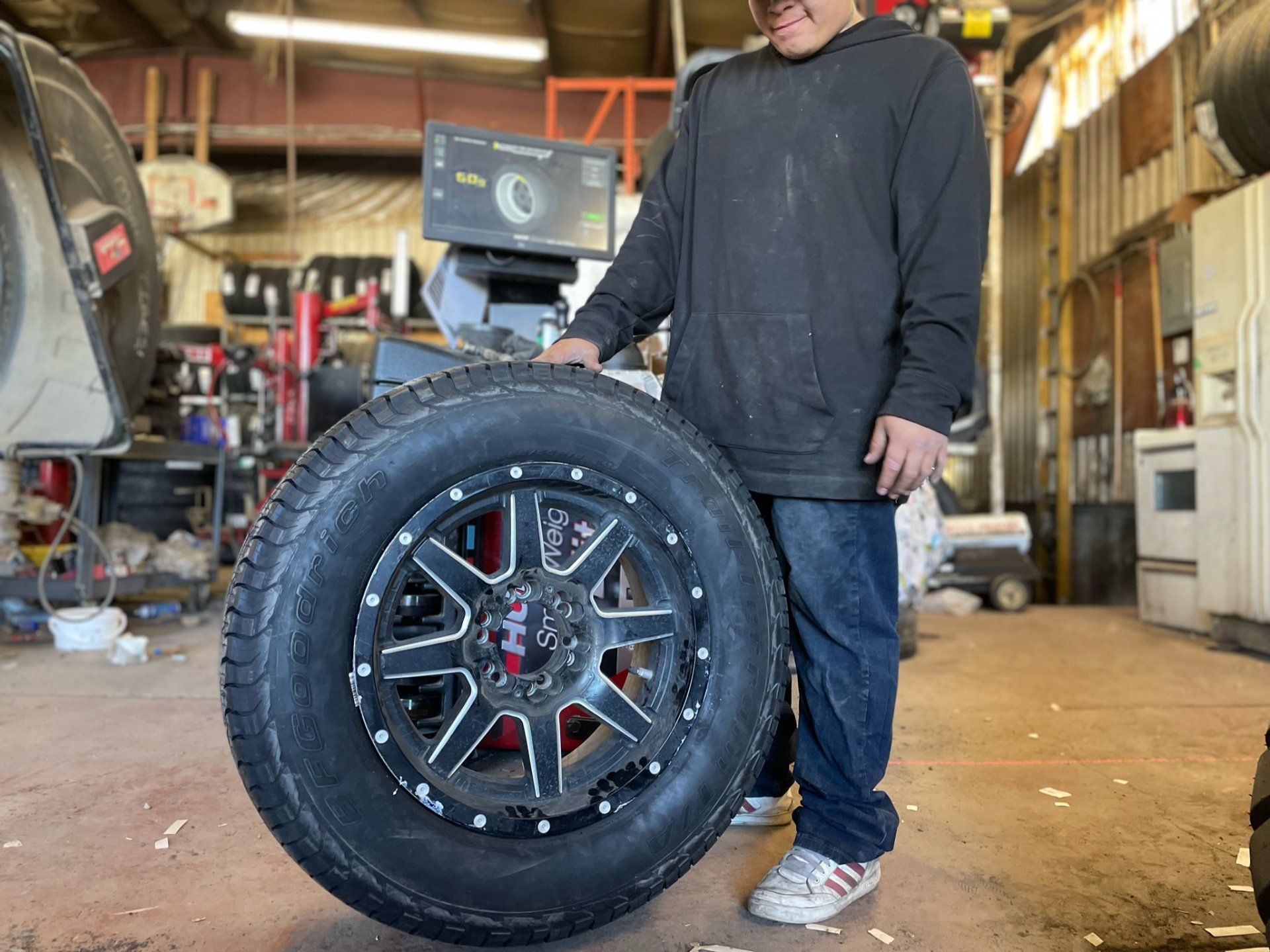technician holding truck tire on grey wheel